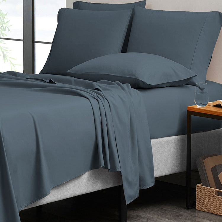 Blue bedding set on a bed with pillows and a side table.