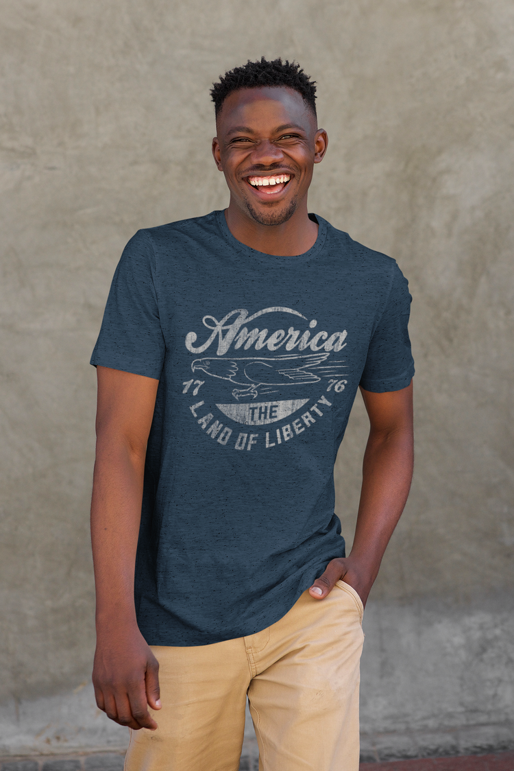 Man wearing a navy blue t-shirt with 'America' graphic against a textured wall.
