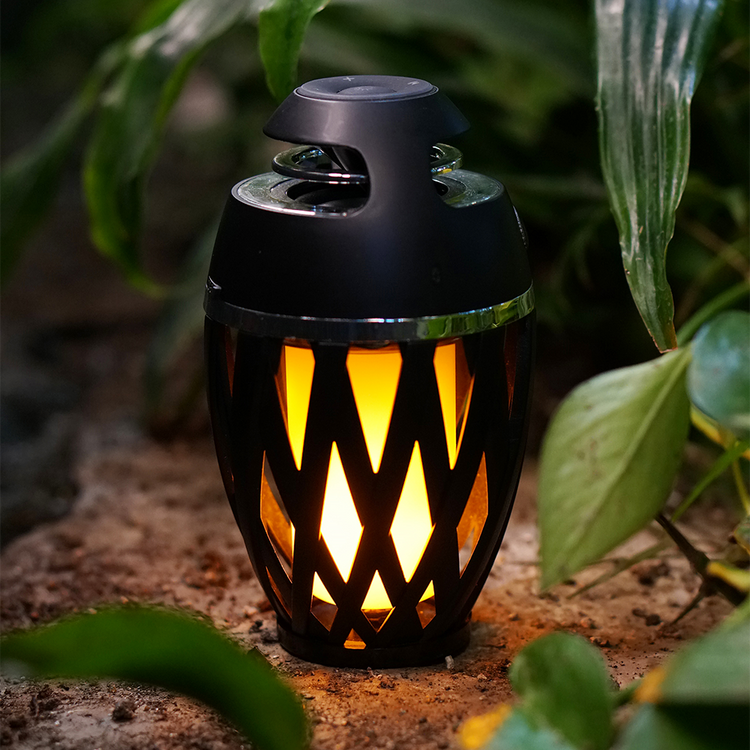 Black lattice-patterned lantern with warm glow on a natural background