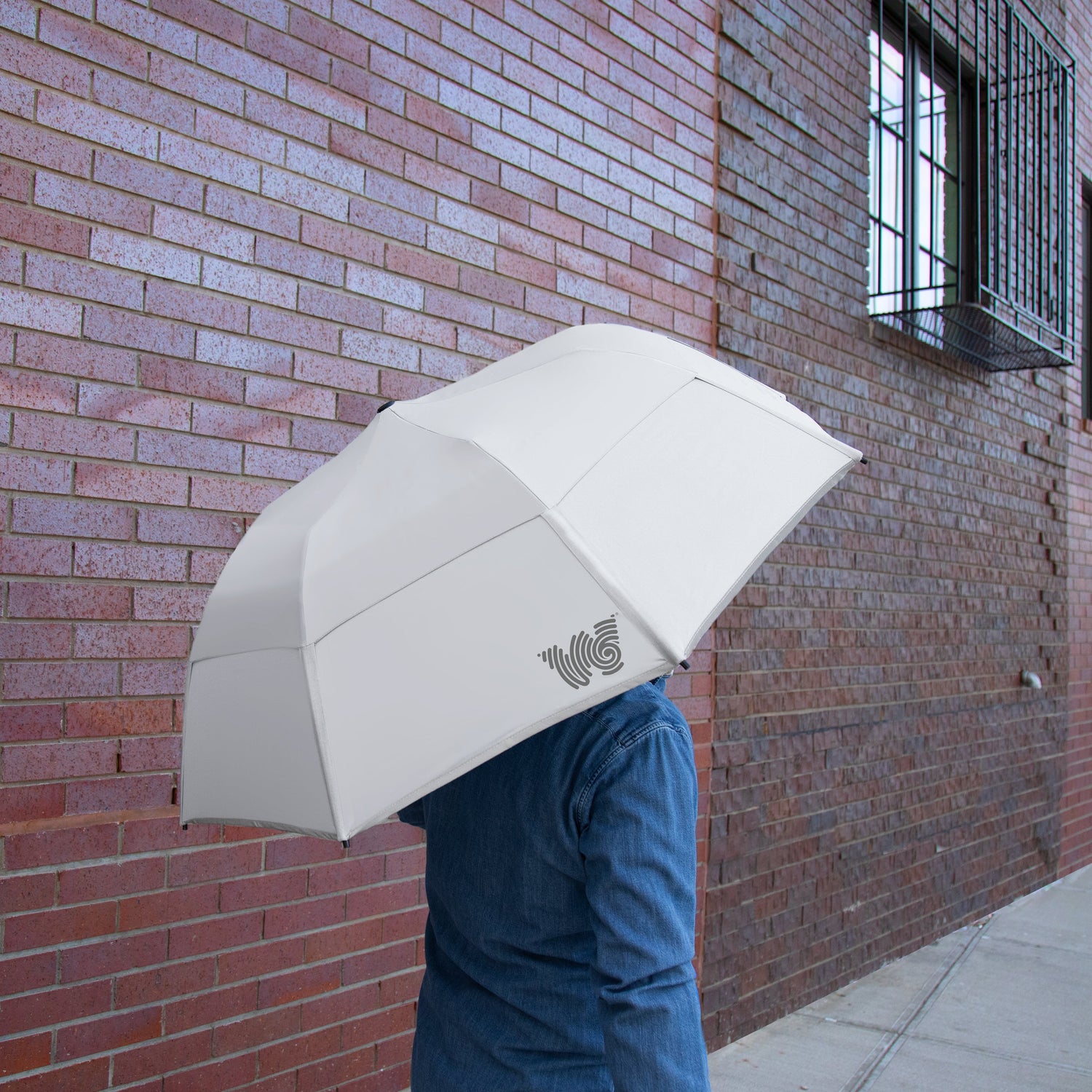 Person walking on sidewalk with Weatherman Collapsible Umbrella in white.