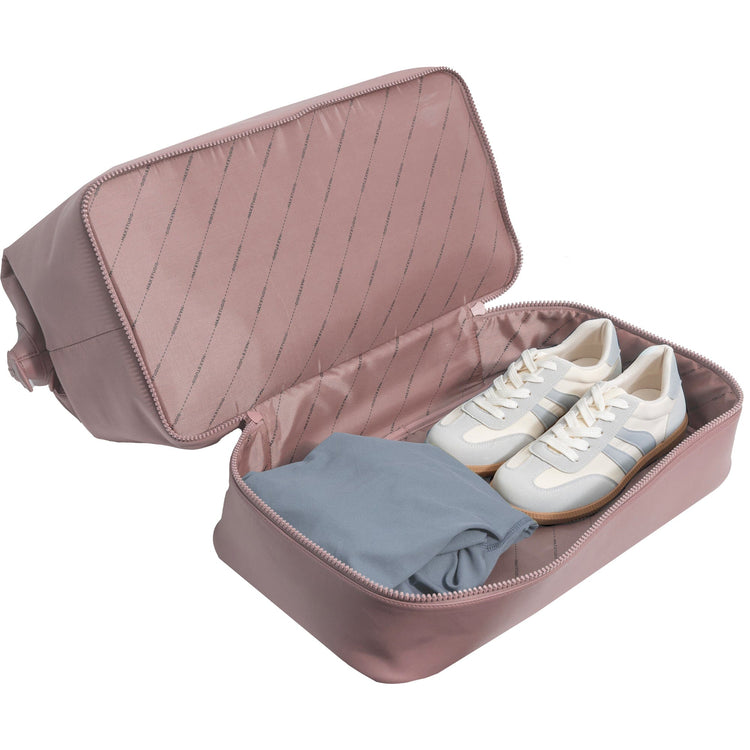 Pink travel shoe organizer with a white sneaker and gray cloth inside on a white background