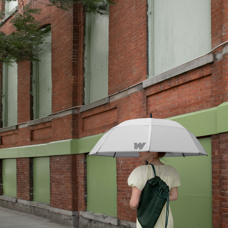 Woman walking with opened Weatherman Stick Umbrella in white.
