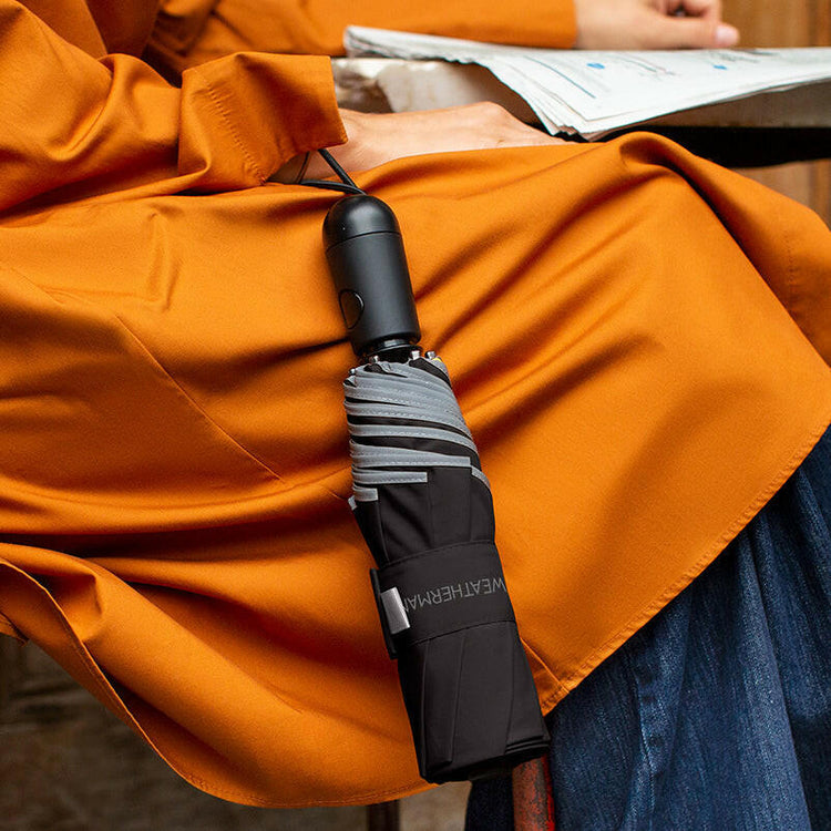 Person holding Weatherman Travel Umbrella in black.