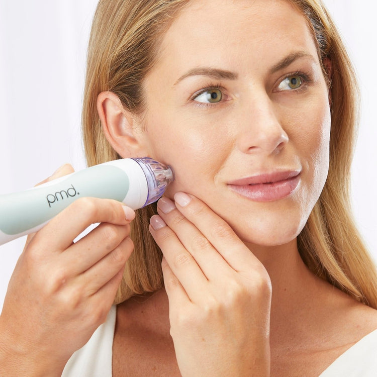 Woman using a Prada skincare device on her face against a white background