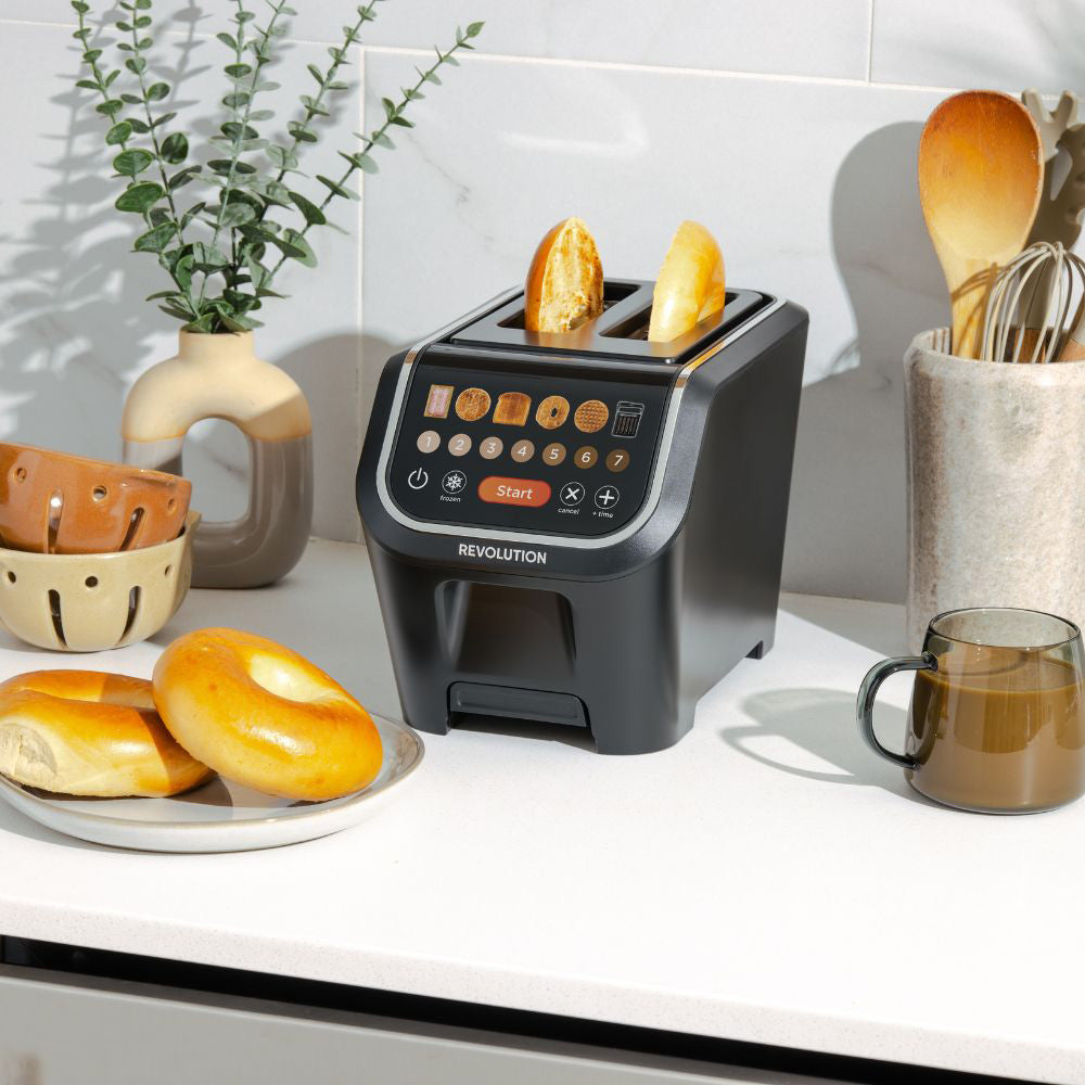 Toaster with bread slices on a kitchen counter with a plant and mug in the background
