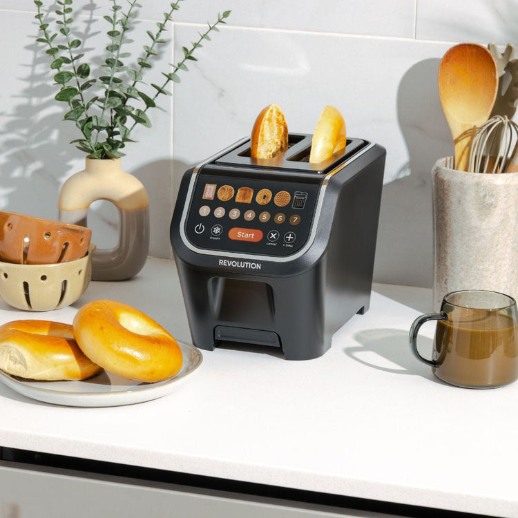 Toaster with bread slices on a kitchen counter with a plant and mug in the background