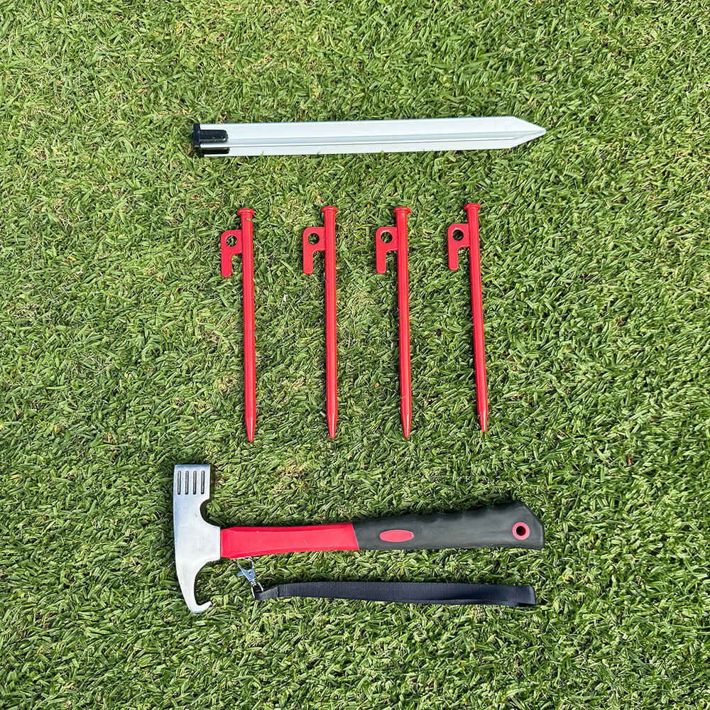 Set of tent stakes, hammer, and strap on grass