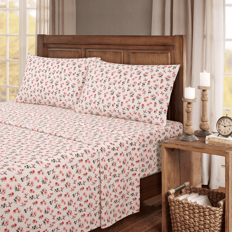 Floral bedspread on a bed with a wooden headboard and nightstand in a bedroom setting.