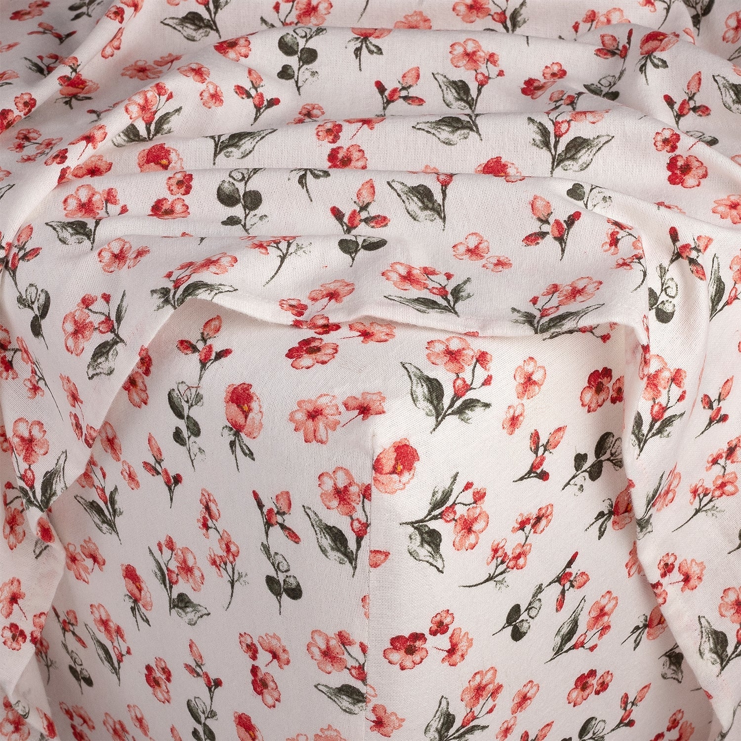 Floral patterned fabric with red flowers and green leaves on a white background
