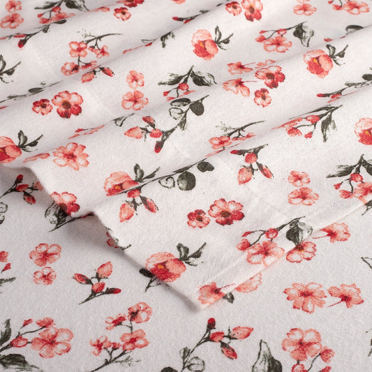 Floral bedspread on a bed with a wooden headboard and nightstand in a bedroom setting.