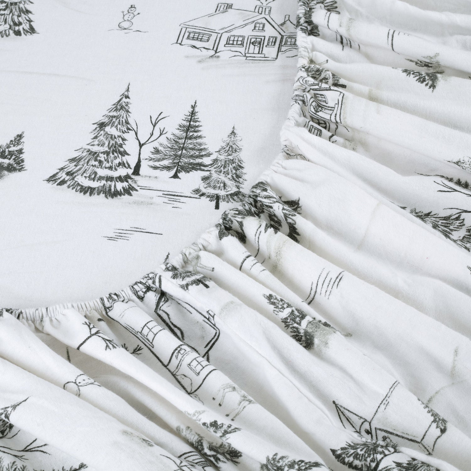 Stack of white fabric rolls with black winter-themed patterns including houses, trees, and snowmen.