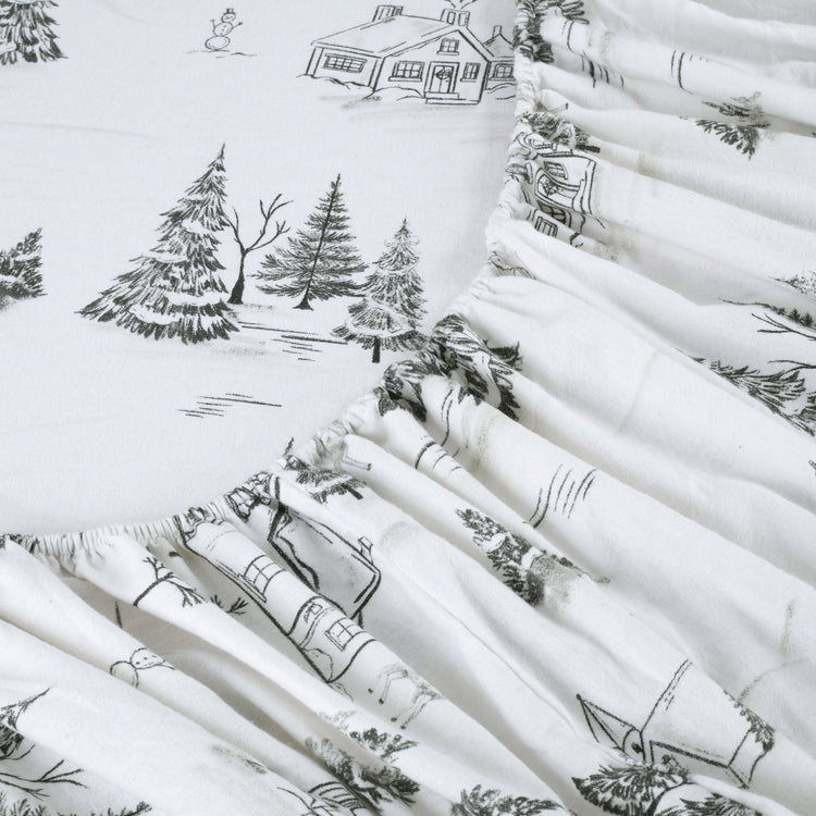 Stack of white fabric rolls with black winter-themed patterns including houses, trees, and snowmen.