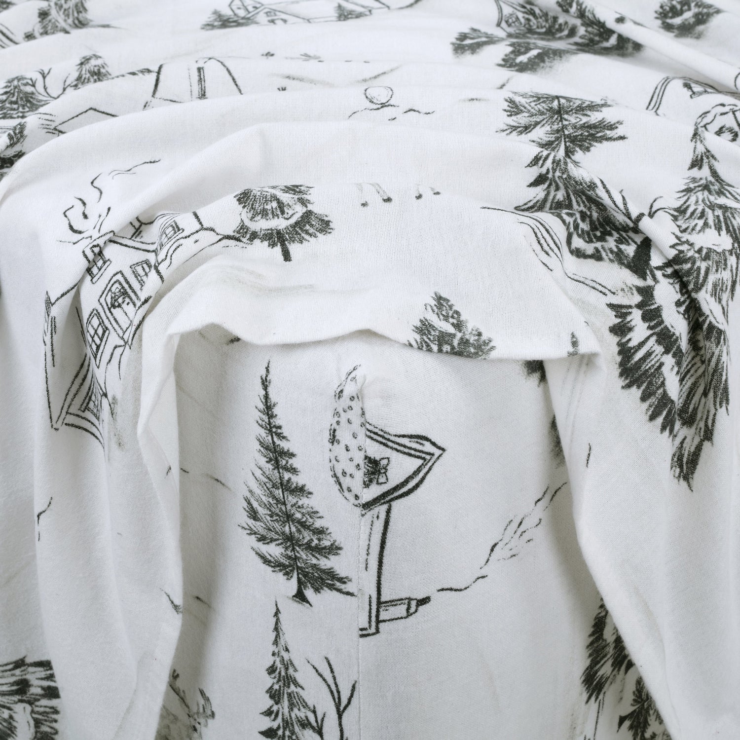 White fabric with black nature-themed illustrations, including trees and houses.