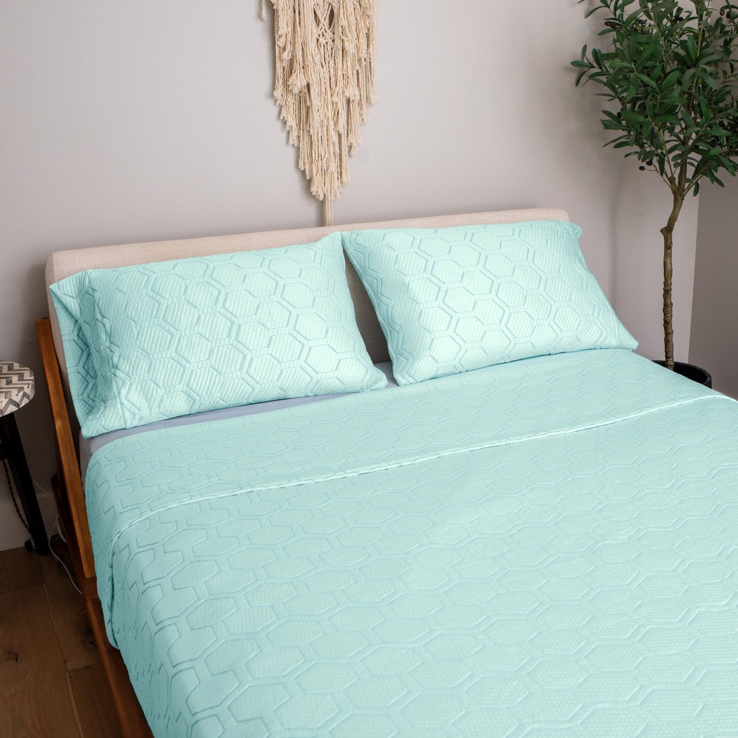 Teal quilted bedspread and pillowcases on a bed in a bedroom setting.