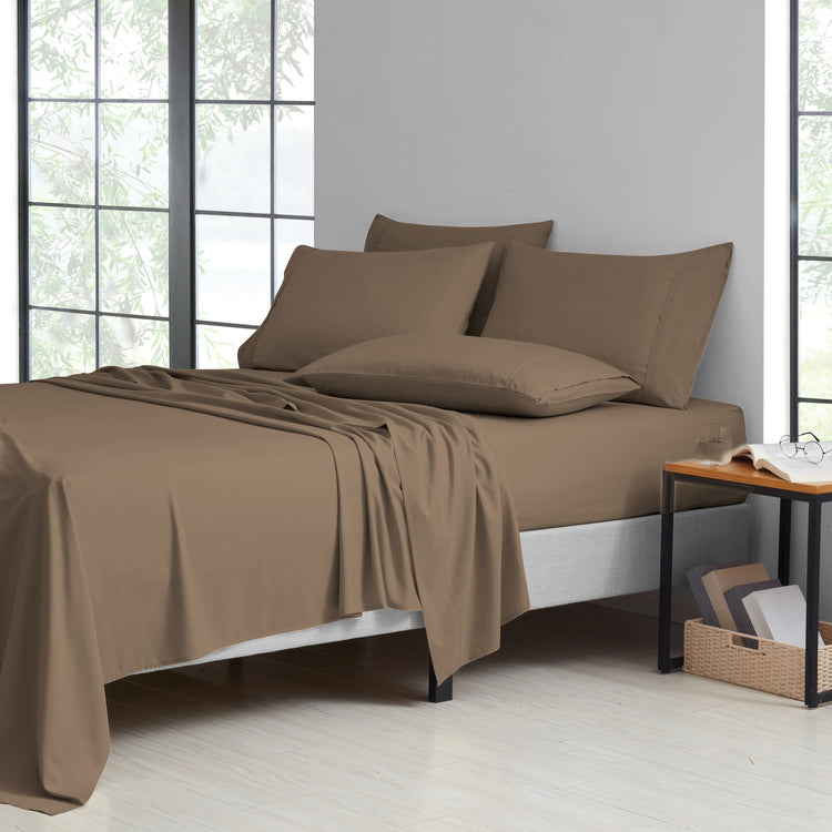 Brown bed sheets and pillows on a bed in a room with large windows.