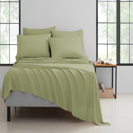 Green bedding set on a bed in a room with large windows.