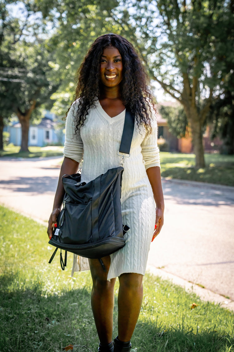 Woman holding a backpack outdoors on a sunny day