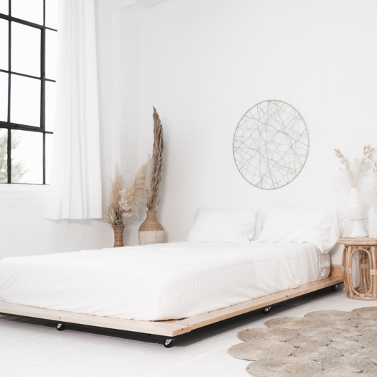 Minimalist bedroom with a bed, decorative plants, and wall art.