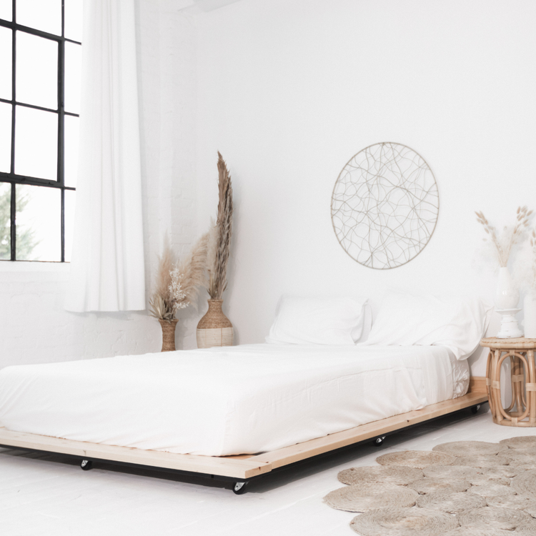Minimalist bedroom with a bed, decorative plants, and wall art.