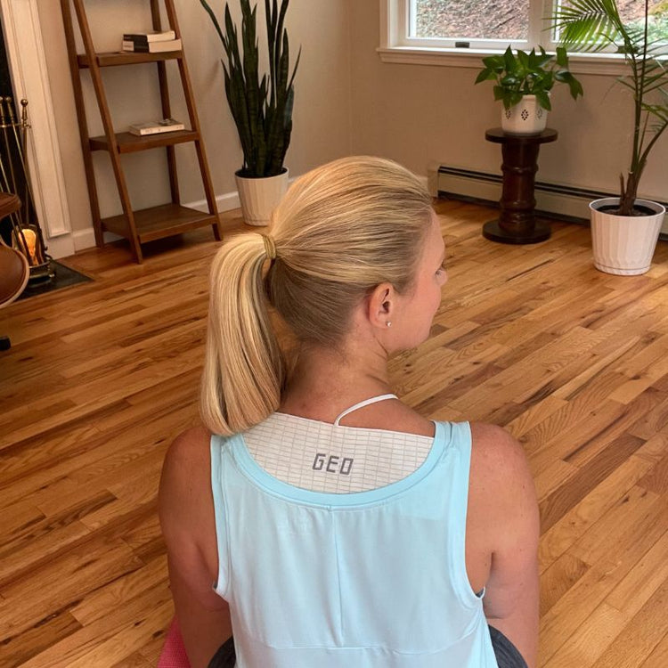 Woman sitting on a chair in a room with wooden flooring and plants.