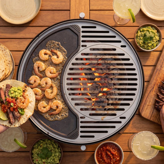 Portable grill with food being cooked on a wooden table outdoors