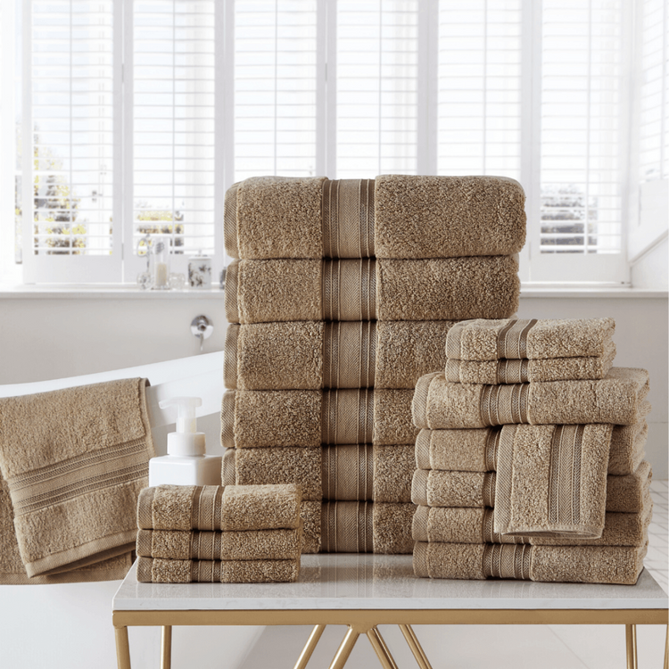 Stacks of beige towels on a table with a window in the background