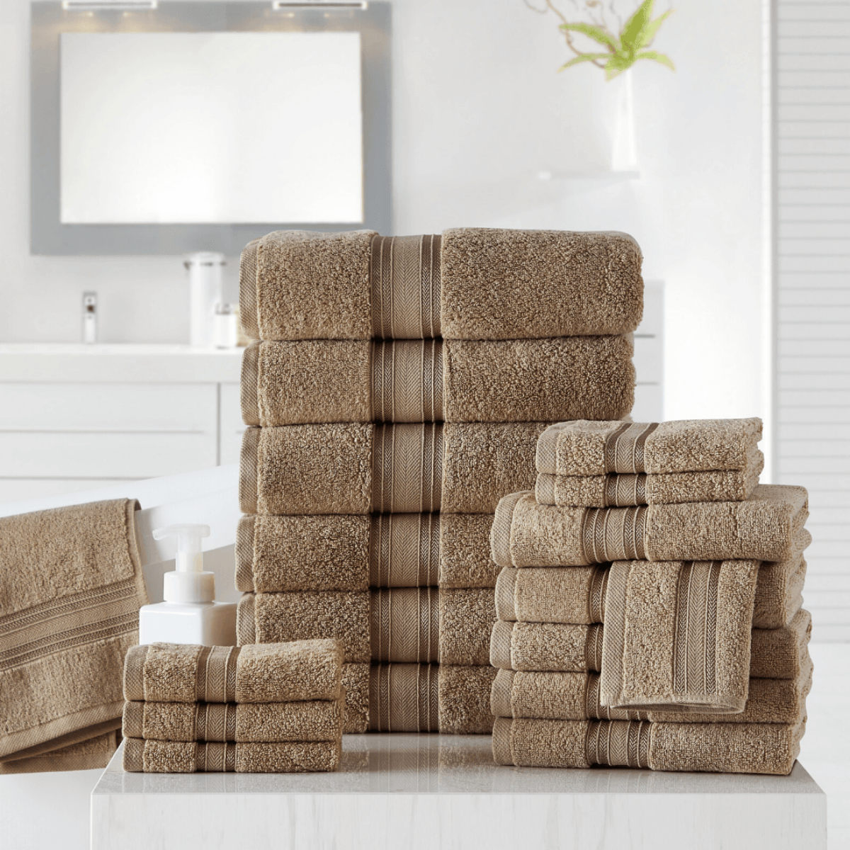 Stack of brown towels on a white surface with a bathroom setting in the background.