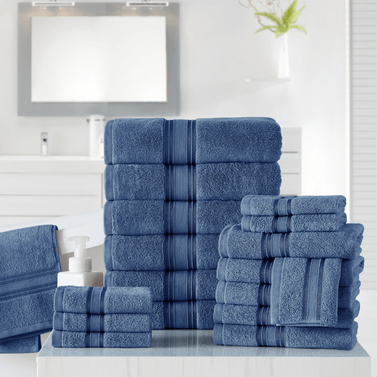 Set of blue towels stacked on a white surface with a mirror in the background.