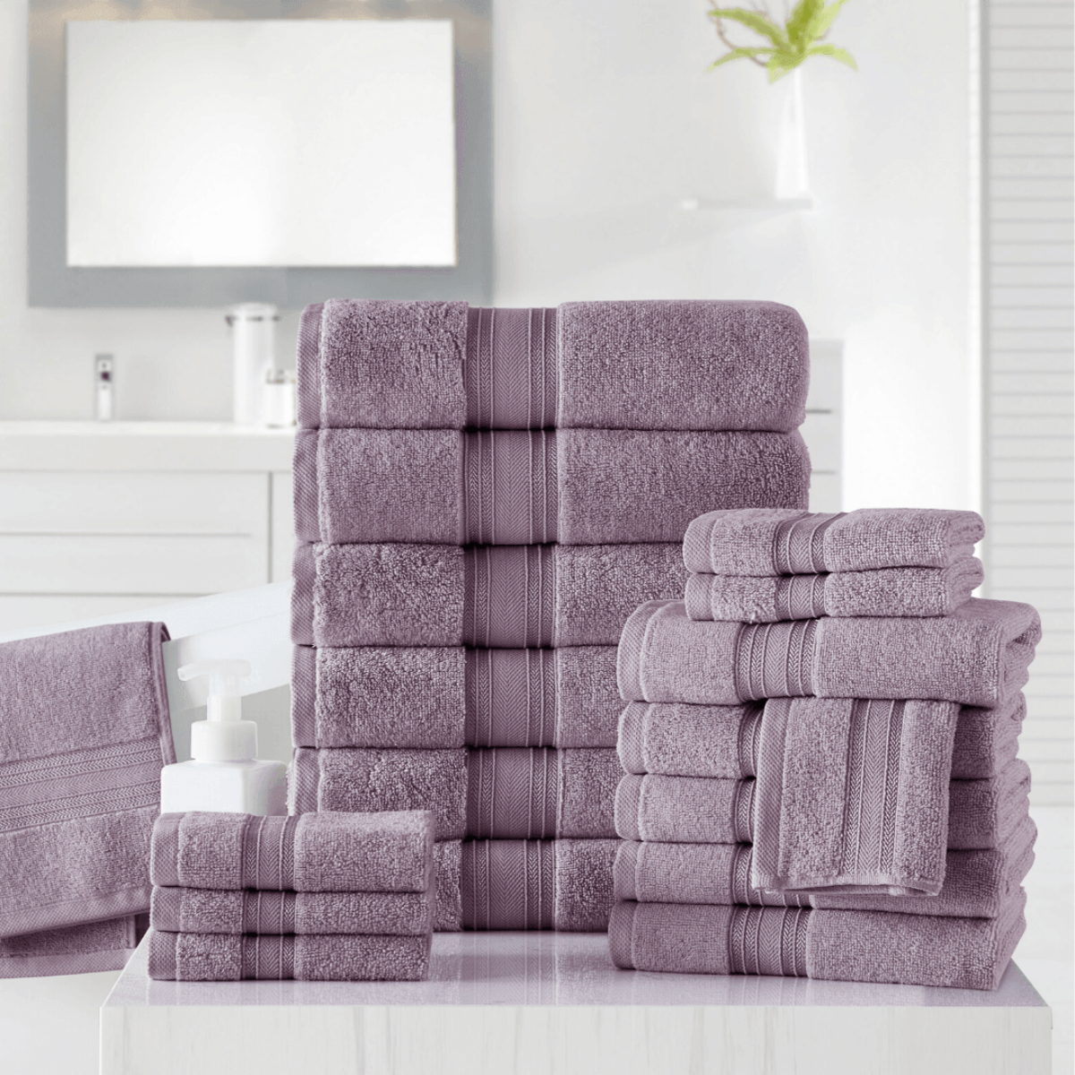 Stack of purple towels on a white surface with a bathroom setting in the background