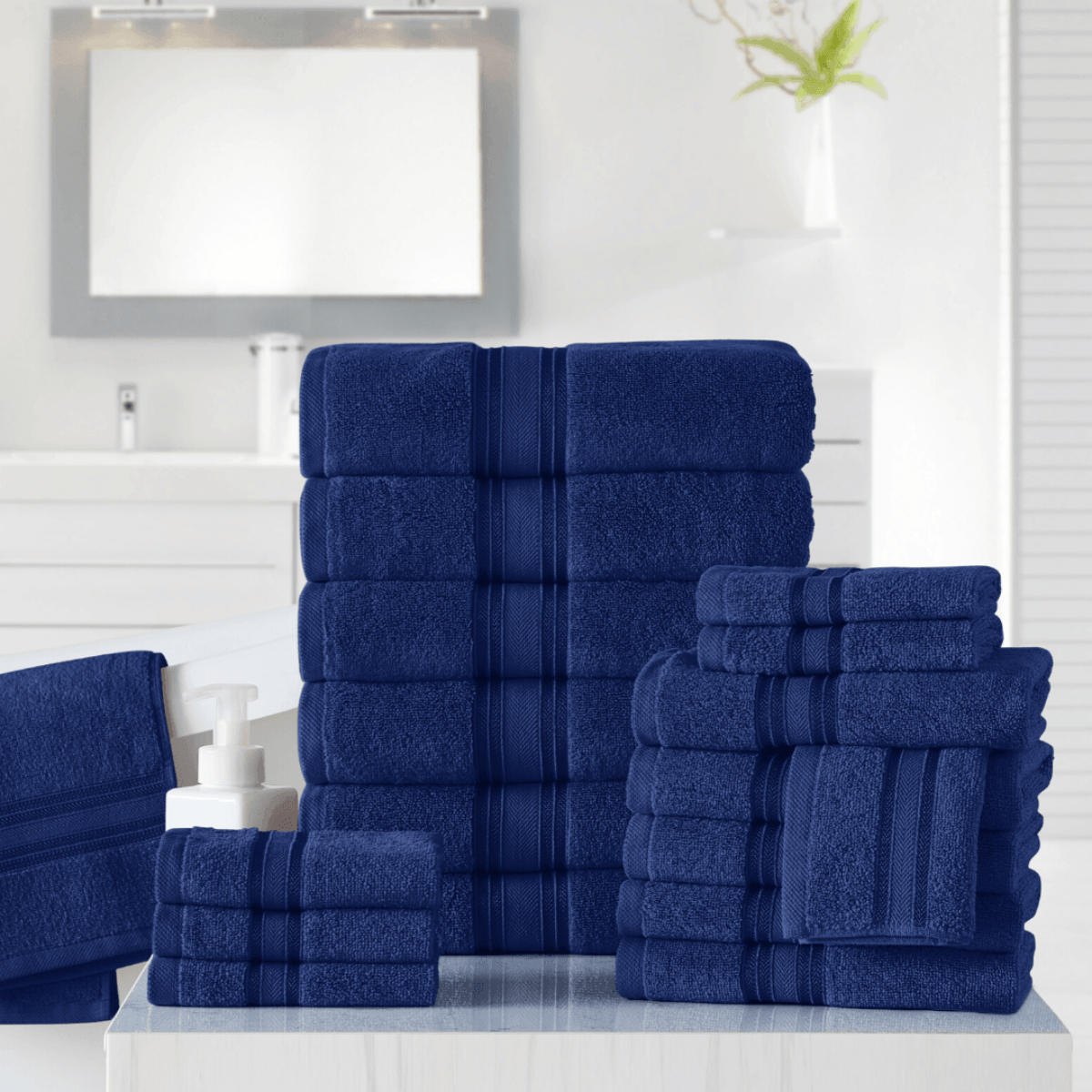 Set of blue towels on a white surface with a mirror and plant in the background