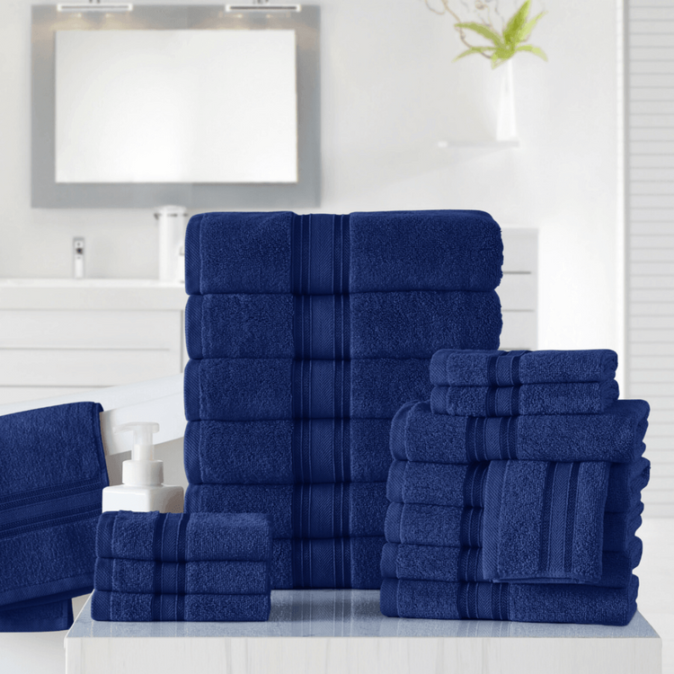 Set of blue towels on a white surface with a mirror and plant in the background