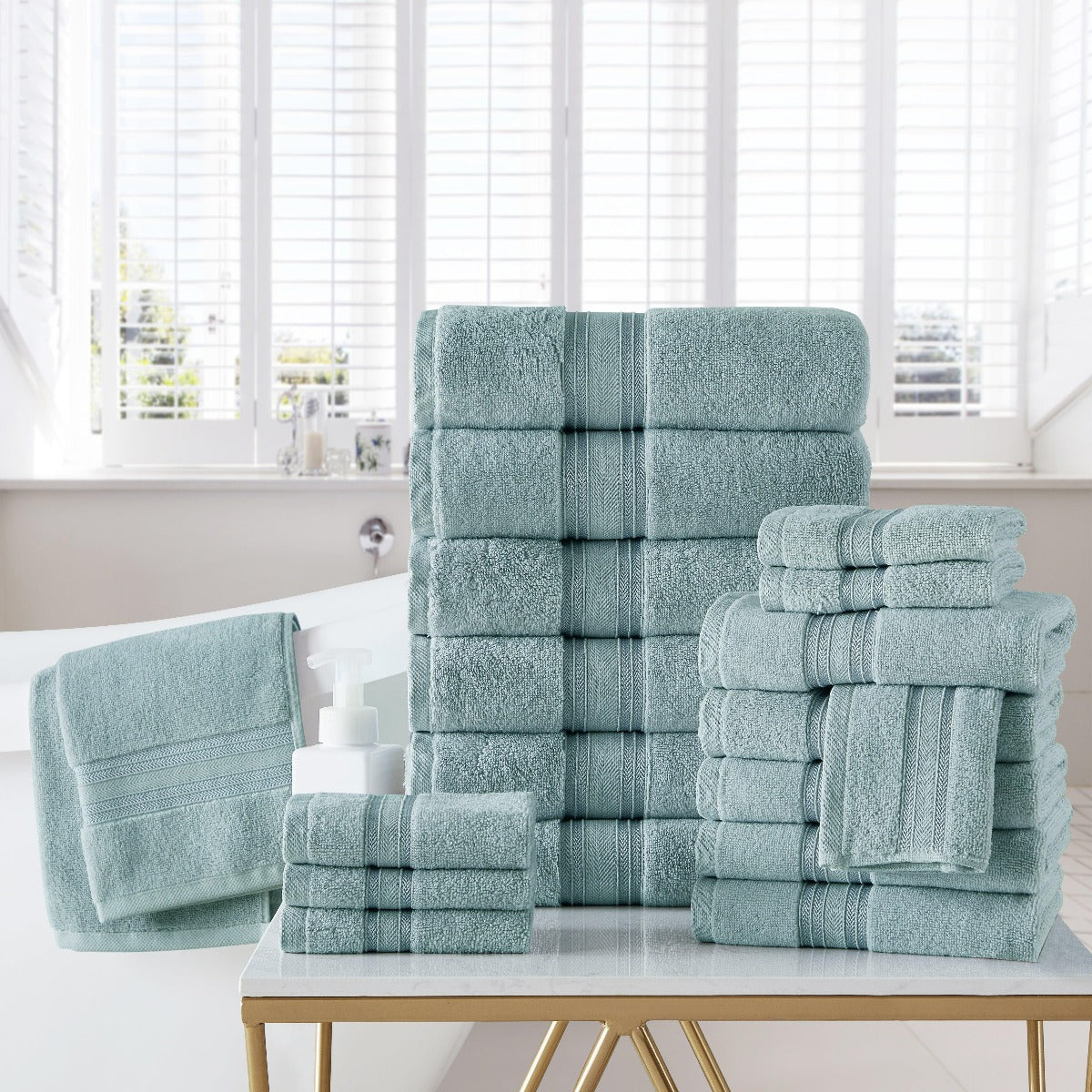 Set of teal towels stacked on a table with a window in the background