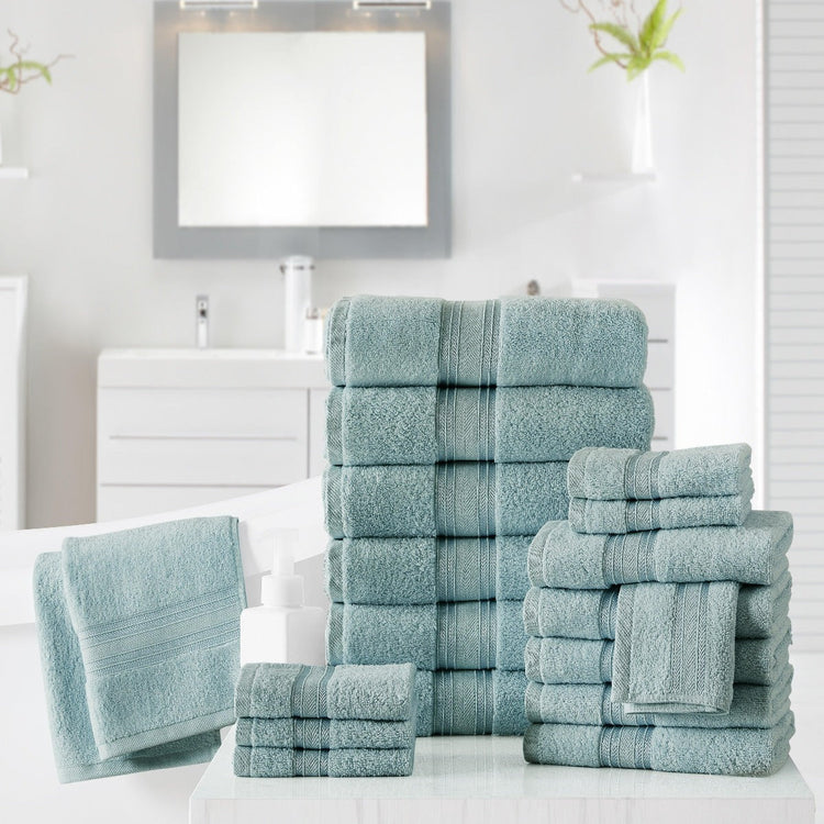 Stack of teal towels on a white surface with a mirror and plant in the background