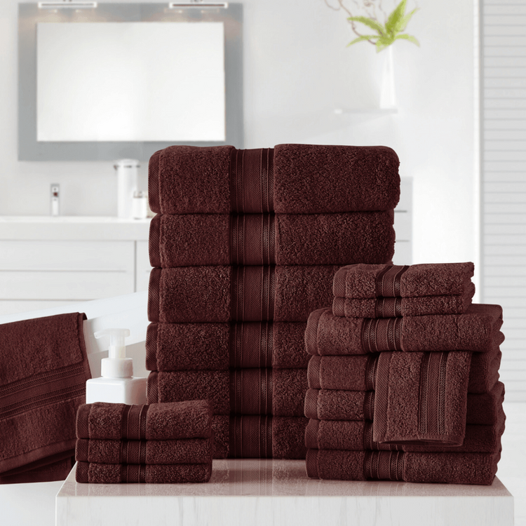 Stack of brown towels on a white surface with a mirror and plant in the background