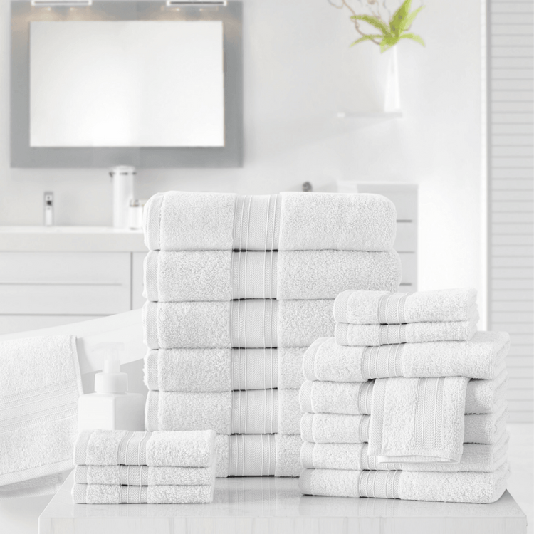 Stacks of white towels on a bathroom counter with a mirror in the background.