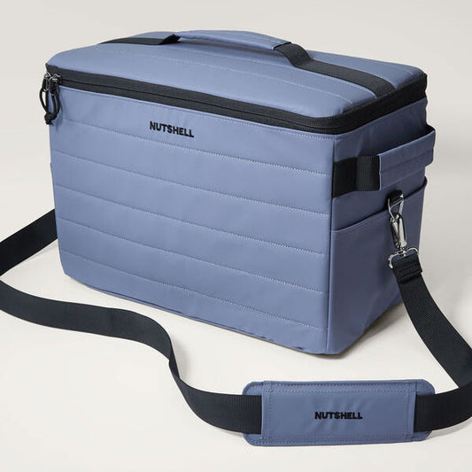 Blue cooler bag with black shoulder strap on a light gray background