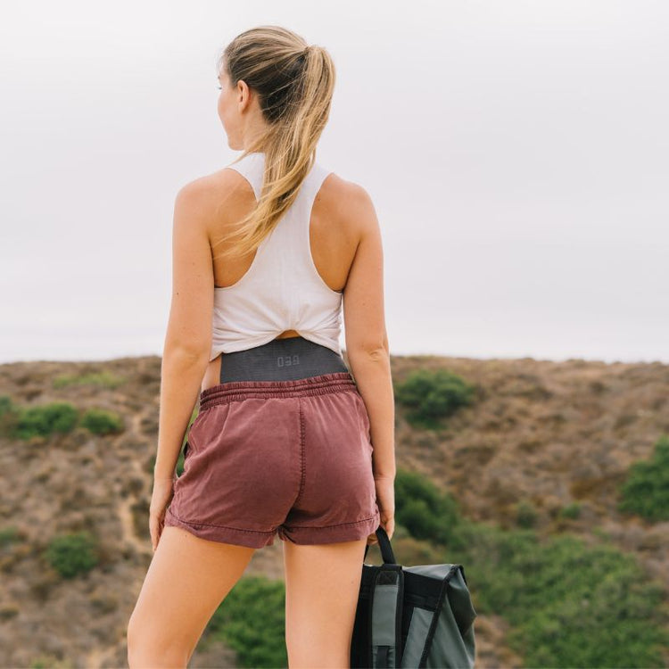 Woman in athletic wear standing on a trail with a scenic background with the GEO devide in the back