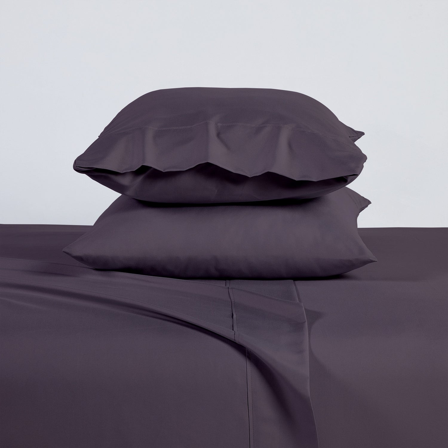 Purple bed sheets and pillows on a plain background