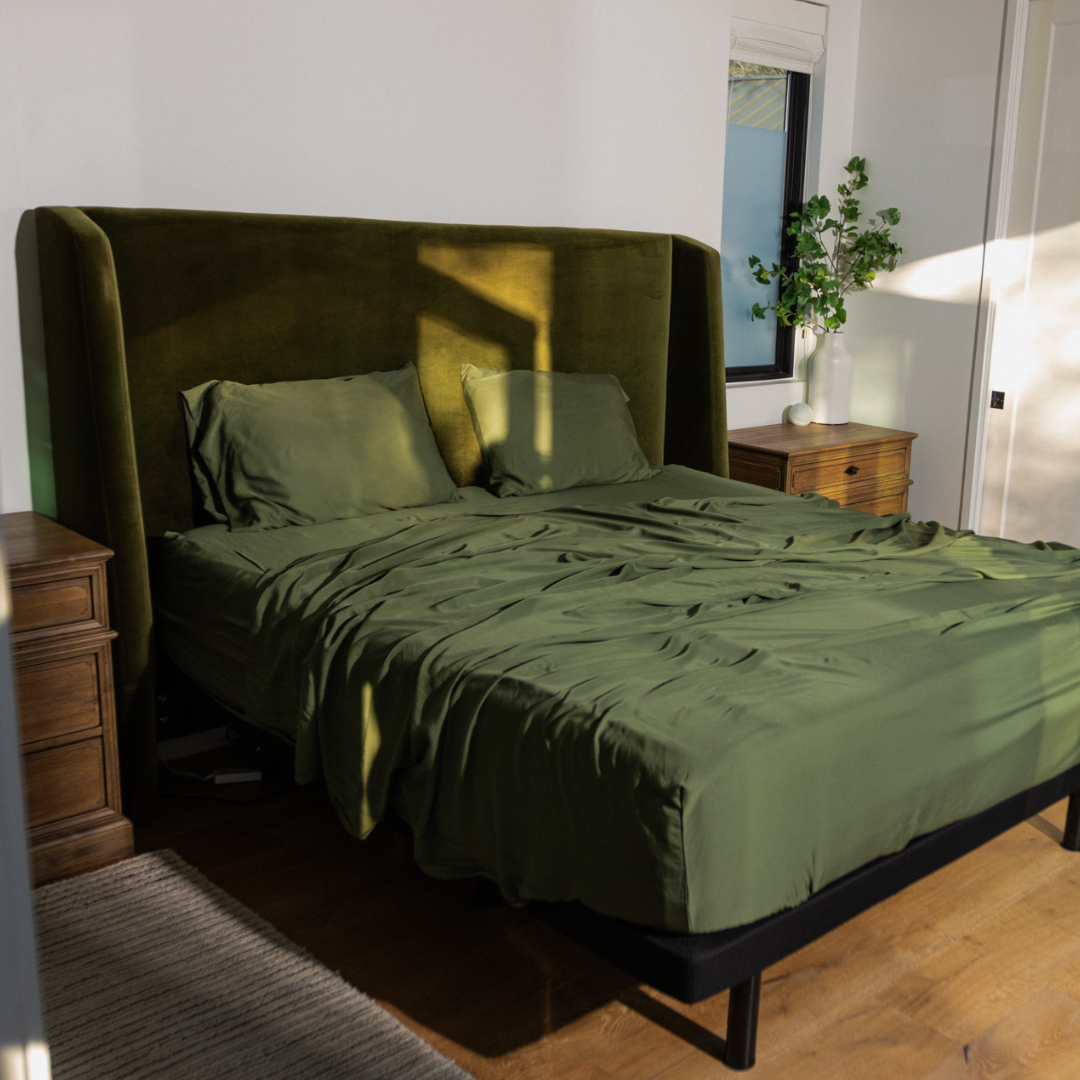 Green bedspread on a bed with wooden nightstands in a bedroom setting