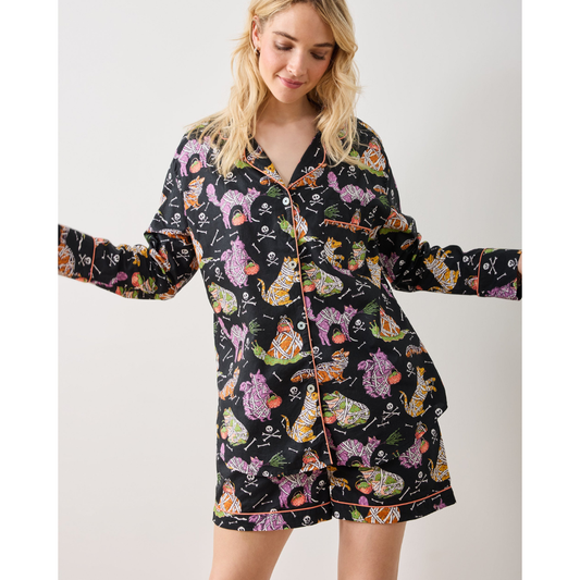 Woman wearing a black pajama top with colorful cat pattern outdoors.