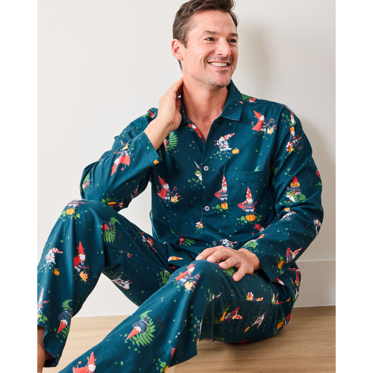 Man wearing a festive teal pajama set with colorful patterns, sitting on a wooden floor.