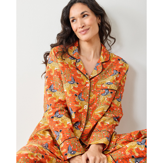 Woman wearing a patterned orange pajama set against a plain background