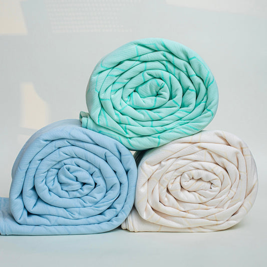 Teal quilted bedspread and pillowcases on a bed in a bedroom setting.