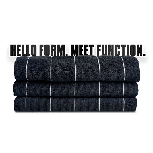 Stack of dark blue towels with white stripes and a red label on a white background