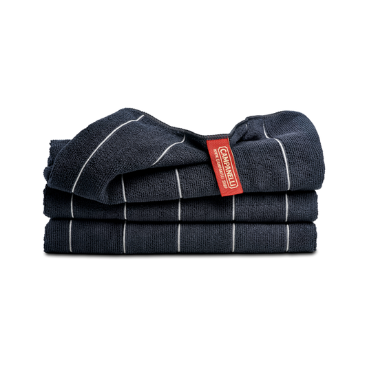Stack of dark blue towels with white stripes and a red label on a white background