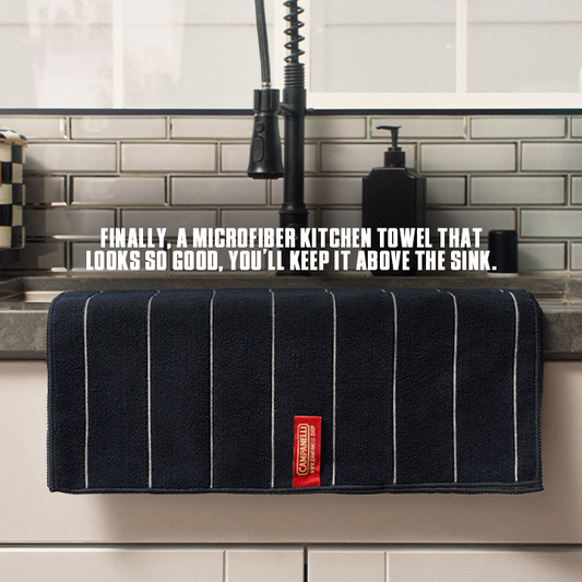 Stack of dark blue towels with white stripes and a red label on a white background