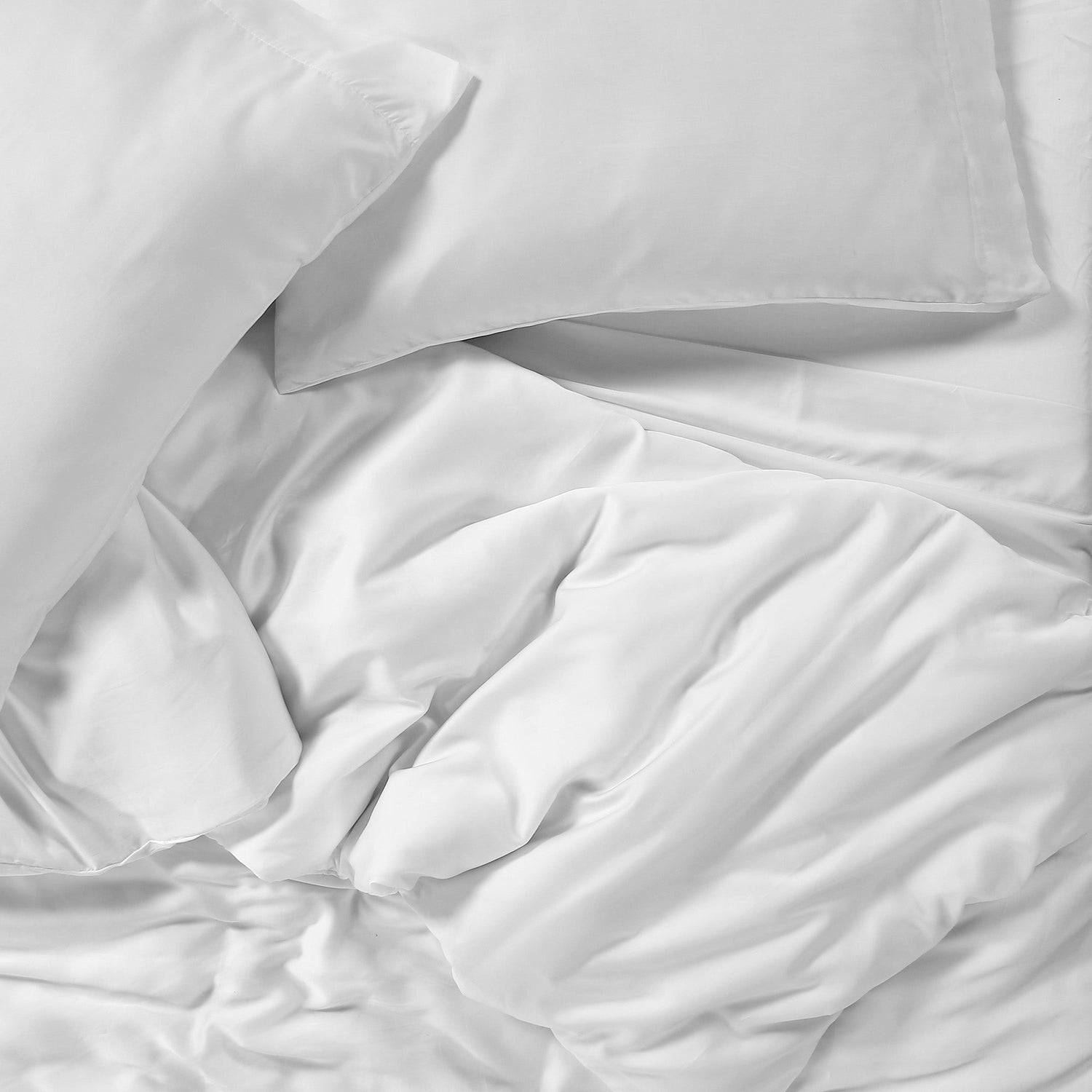 White bedding set with duvet and pillows on a neutral background