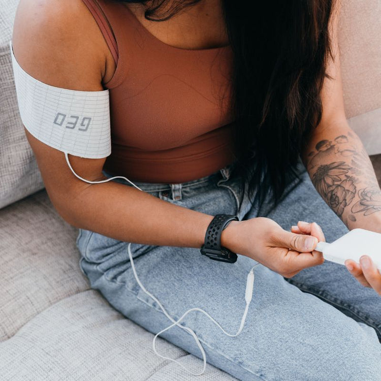 Person sitting on a couch with an electronic device on their arm