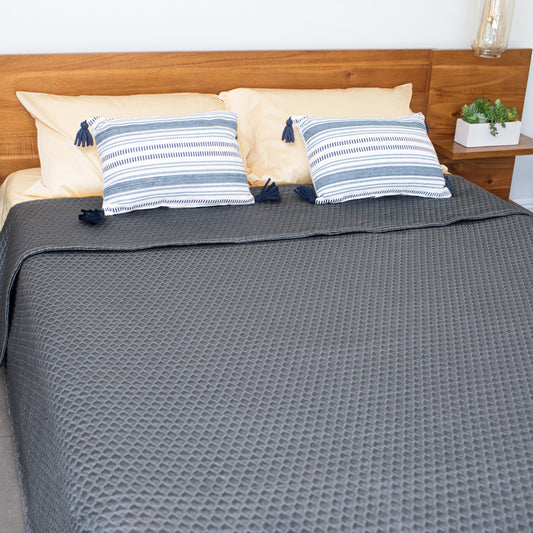 Two people lying in bed facing each other with a pillow between them.