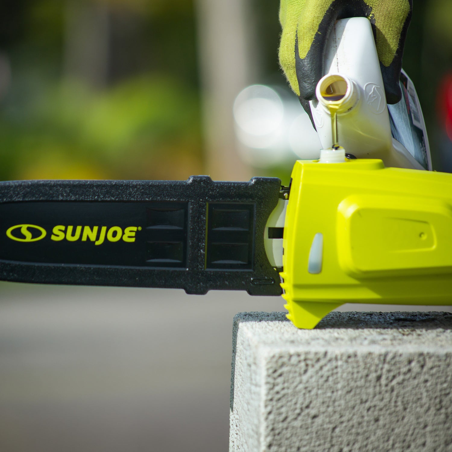 Sun Joe chainsaw on a concrete block with a blurred green background